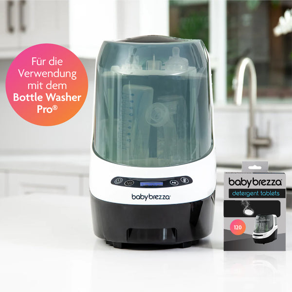 Ein Tischgerät mit der Aufschrift „Baby Brezza“ fasst mehrere Babyflaschen neben einer Schachtel Babybrezza.de Bottle Washer Pro Reinigungstabletten – 120 Stück. Ein rosafarbener Kreis markiert: „Für die Verwendung mit dem Bottle Washer Pro®“ und sorgt so für eine effiziente Babyflaschenreinigung. - product thumbnail